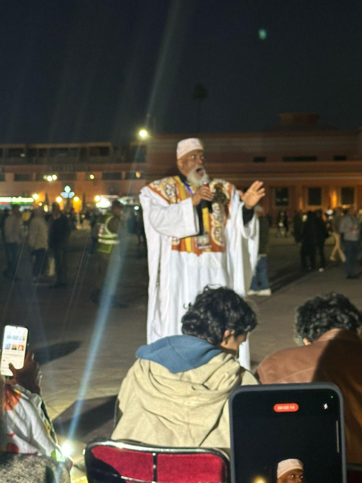 Baba-C telling stories outdoors to a seated audience | Solo AI website creator