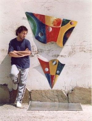 Artist standing beside colorful painted steel plate artwork on a wall | Solo AI website creator