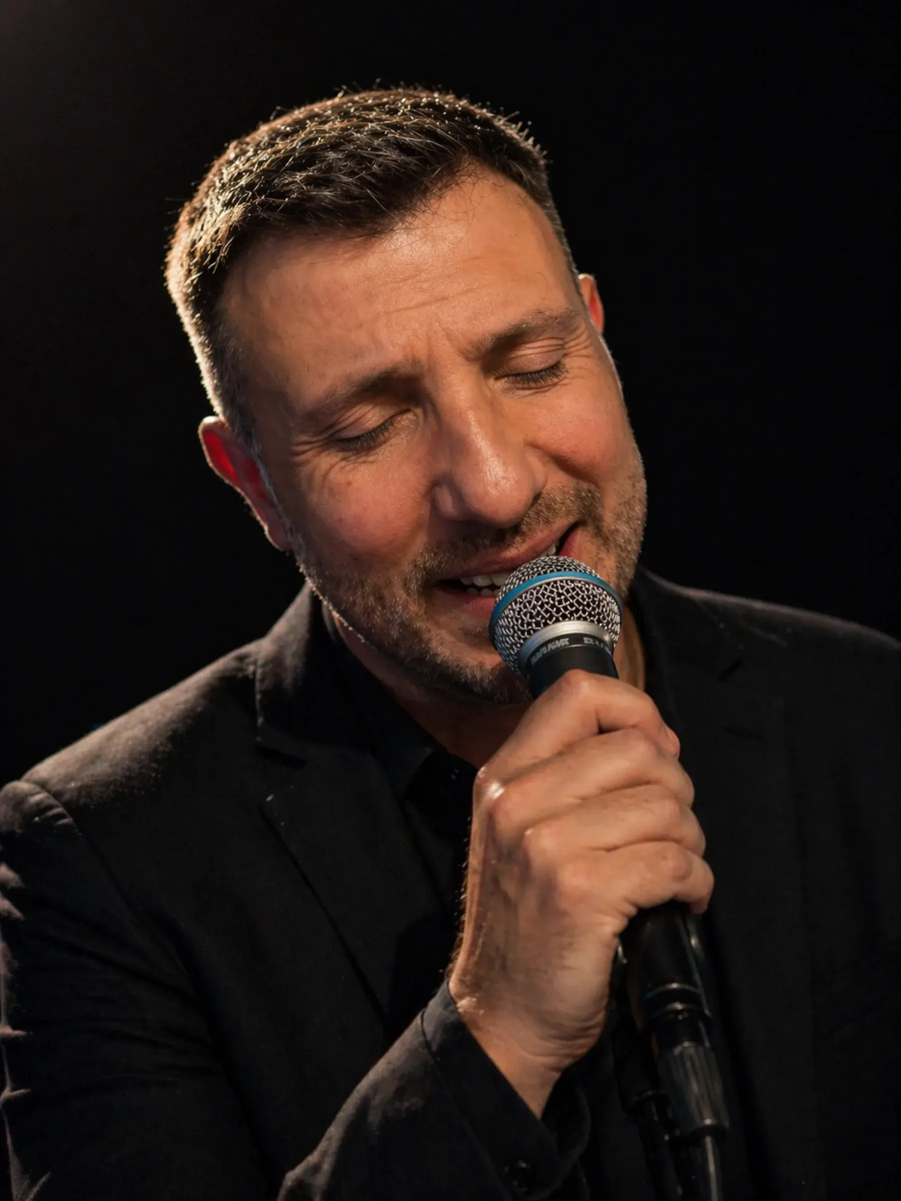 Edoardo Viola singing into a microphone on stage | Solo AI website creator