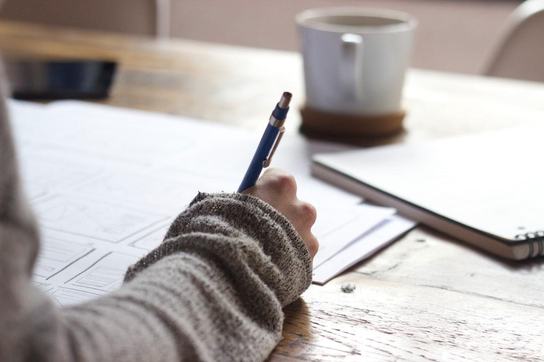 Writer working at desk with pen, notebook, and coffee cup in minimalist workspace setup