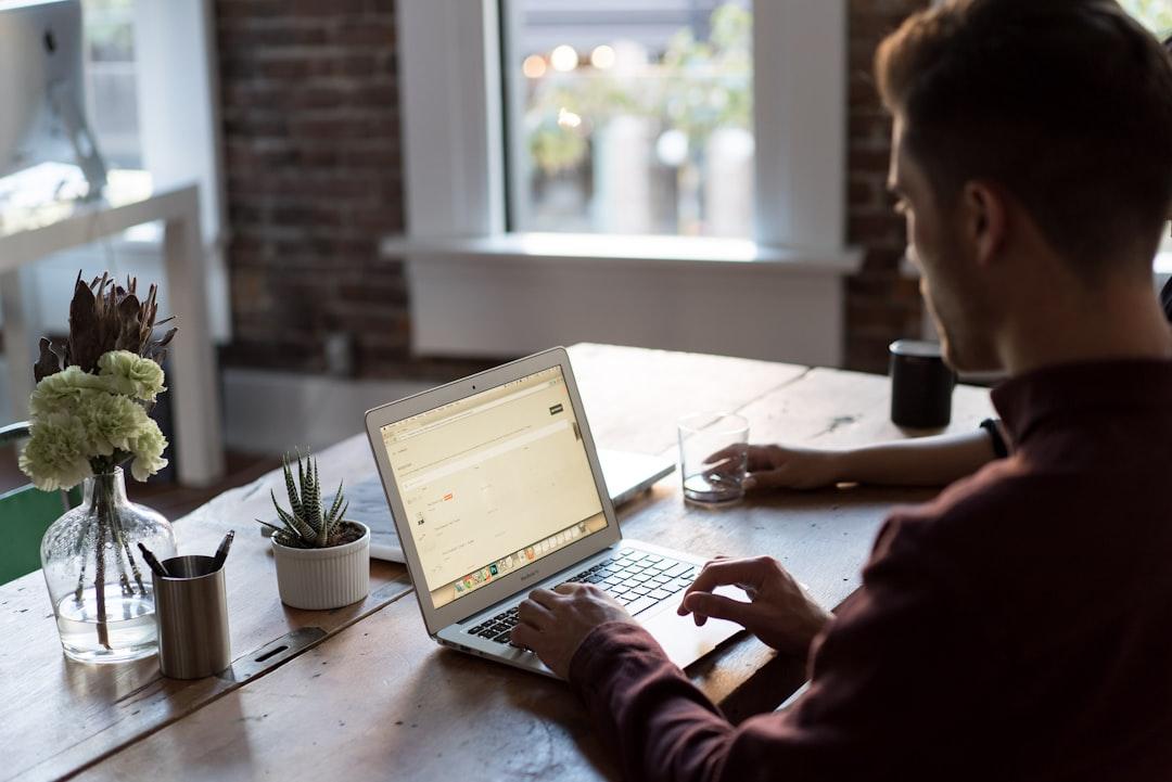 Person working on laptop at desk with plants and coffee, building a website online