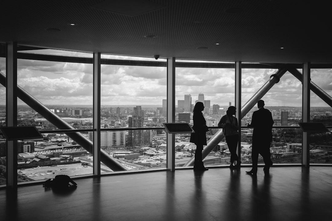 Three business professionals overlooking a city skyline from a high-rise office window